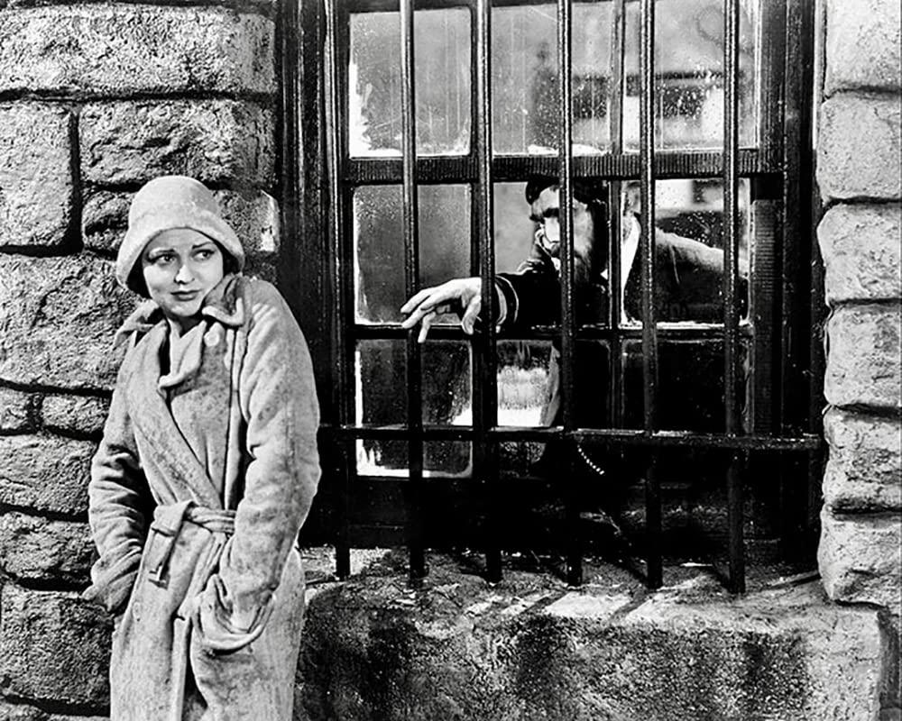 Frau vor Fenster mit Gitter, Mann dahinter.