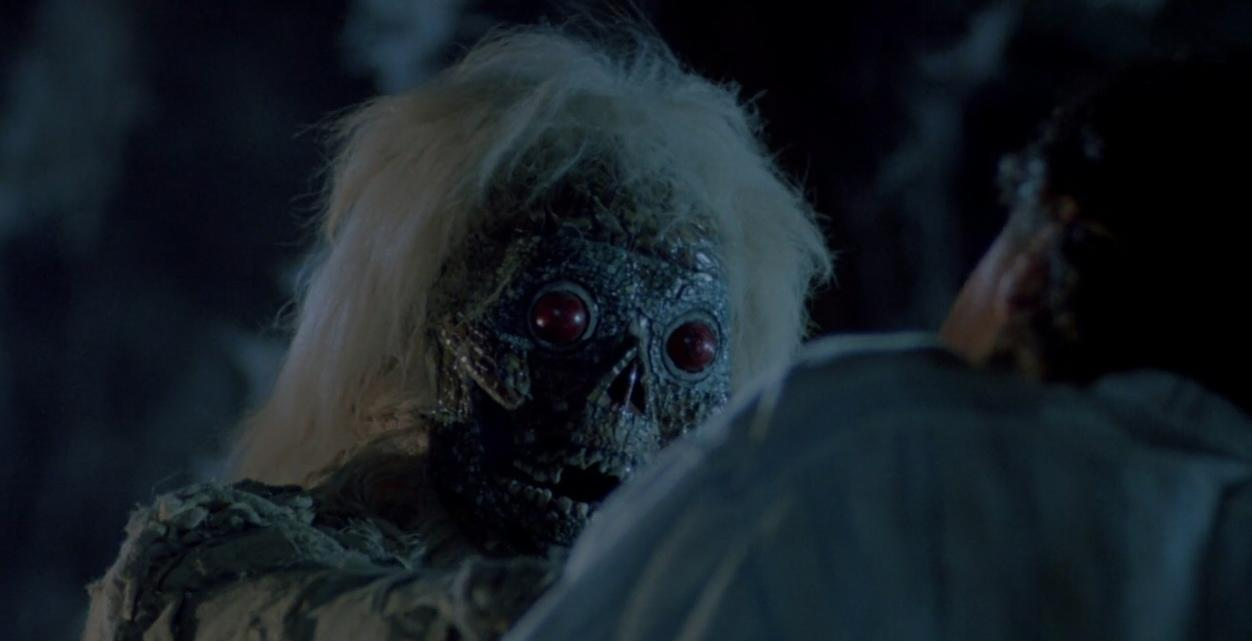 Ein gruseliges Monster mit roten Augen und weißem Haar starrt eine Person an.