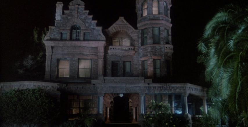 Ein großes, steinernes Herrenhaus bei Nacht, beleuchtet von innen.