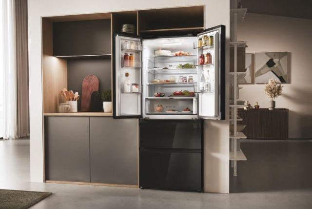 Ein offener Kühlschrank mit Lebensmitteln, in einer modernen Küche mit Holzschränken und Regalen.
