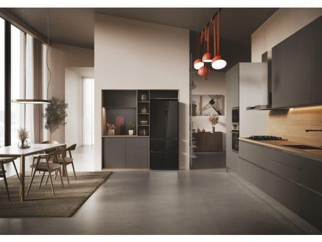 Modernes Esszimmer und Küche mit dunklen Schränken, Holzakzenten und weißen Wänden.