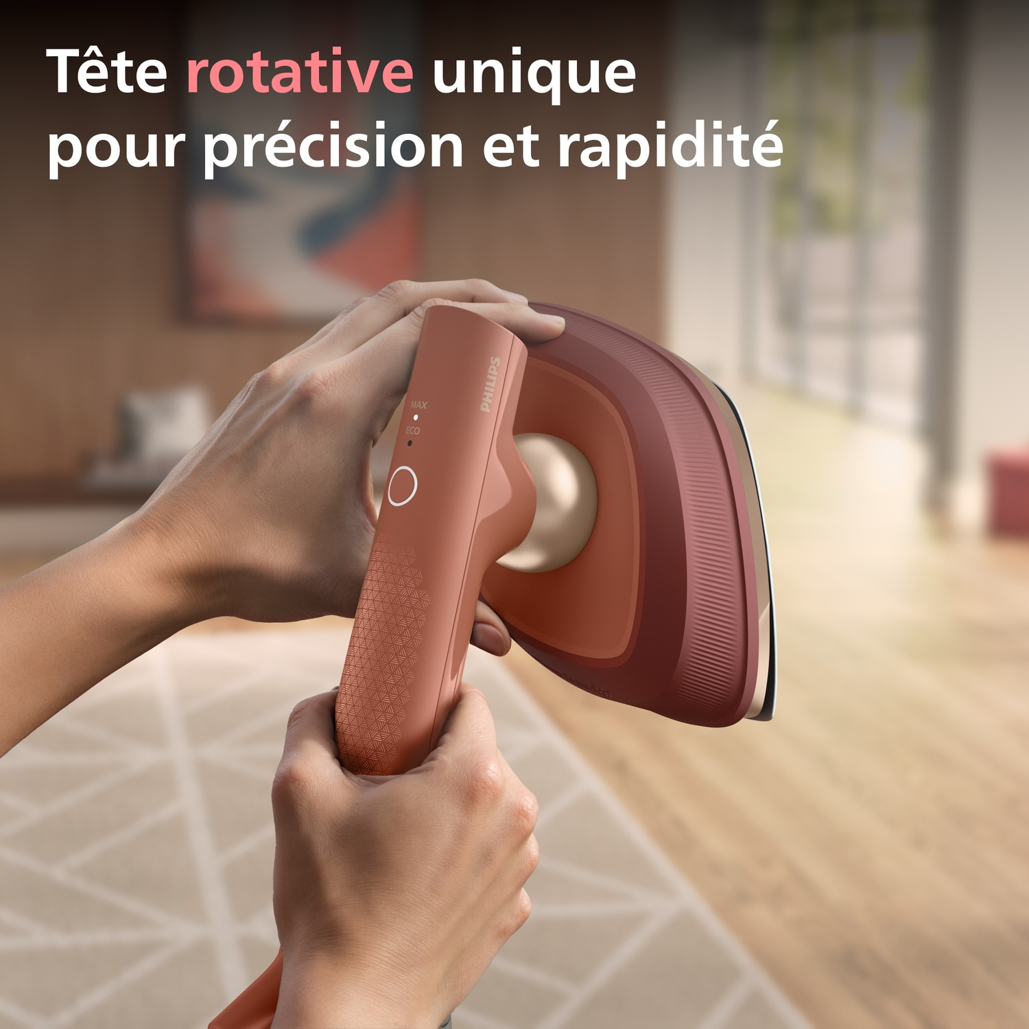 Mains tenant un fer à repasser rose doré à tête rotative unique.