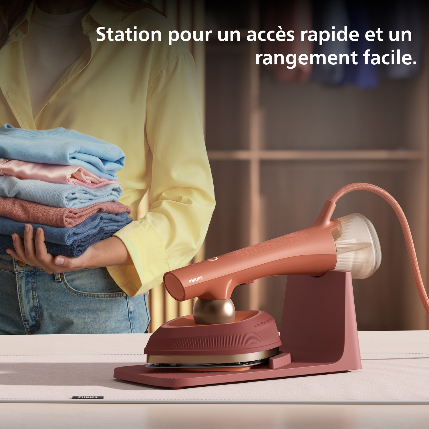 Une personne tient des vêtements, à côté une station de repassage vapeur.