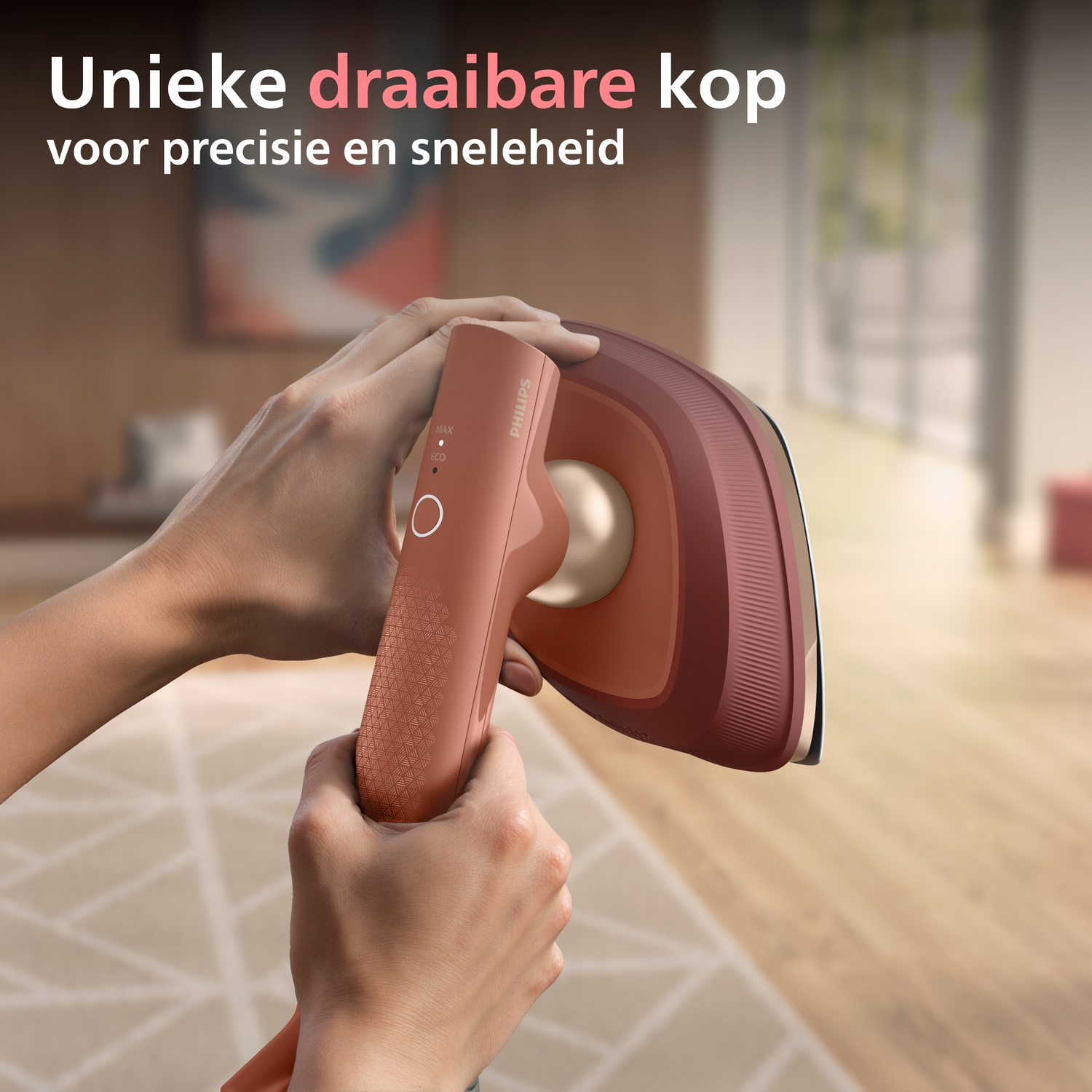 Hands holding a coral-colored Philips steam iron with gold accents.