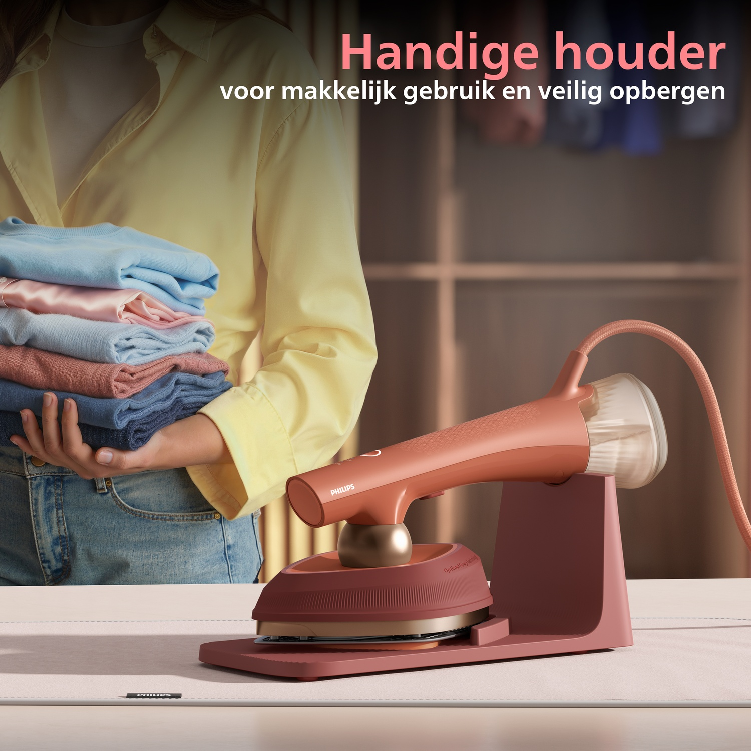 A rose gold garment steamer rests on its charging plate beside stacked clothes.