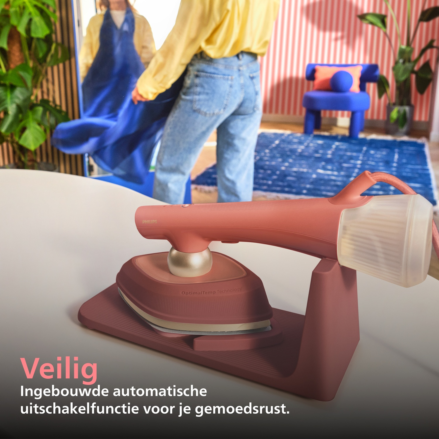 A pink steam iron stand with an iron on a table.