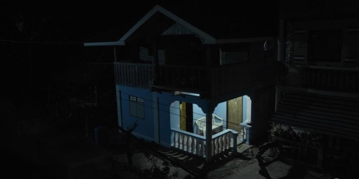 Ein blaues Haus mit zwei Stockwerken bei Nacht, beleuchtete Fenster.