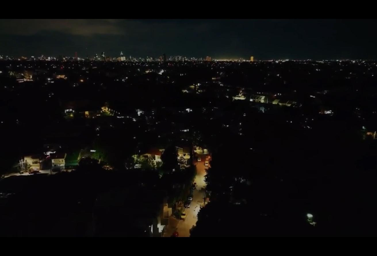 Eine Stadt bei Nacht mit Lichtern und Wolken am dunklen Himmel.