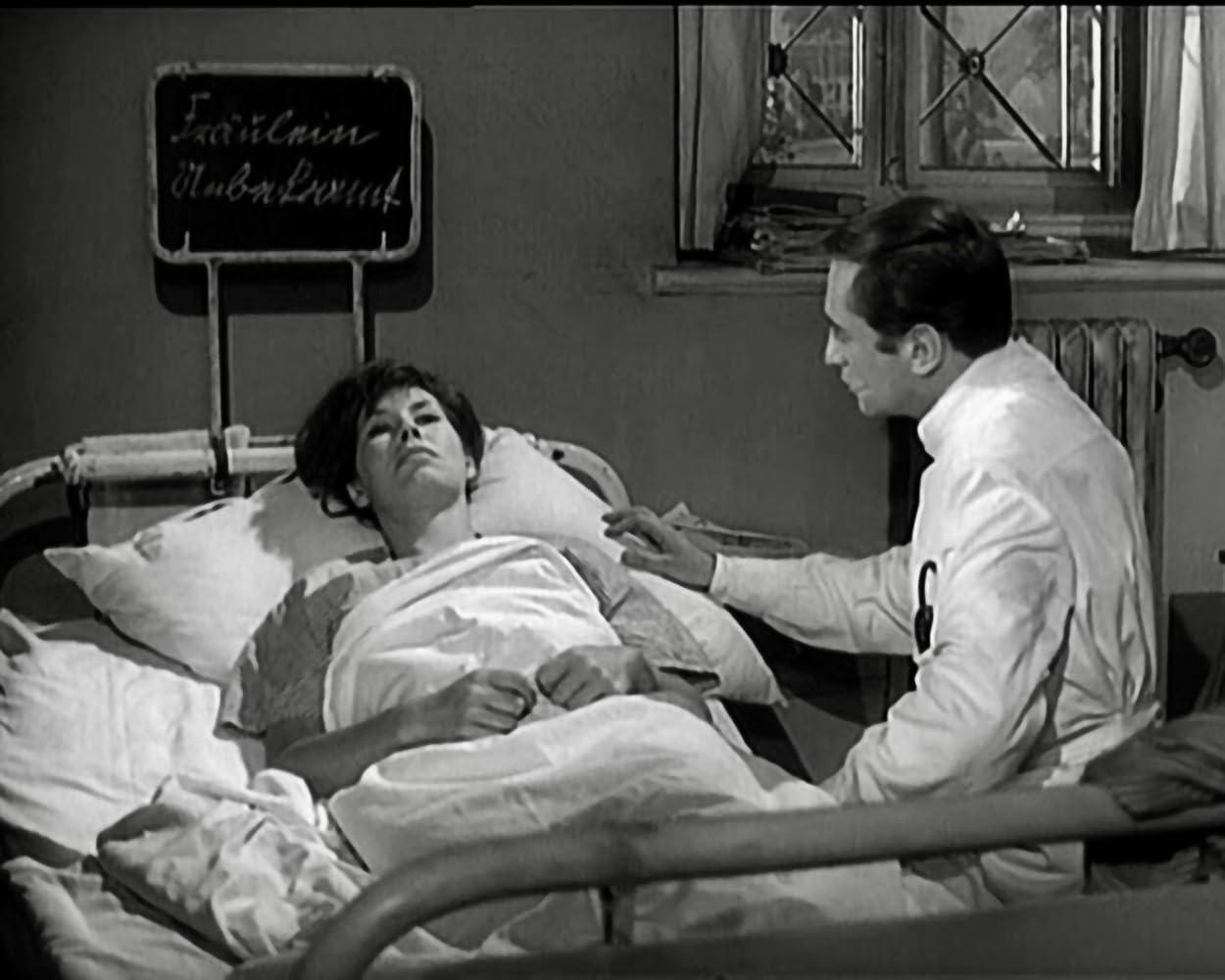 Ein Arzt beugt sich über eine Patientin im Krankenhausbett.