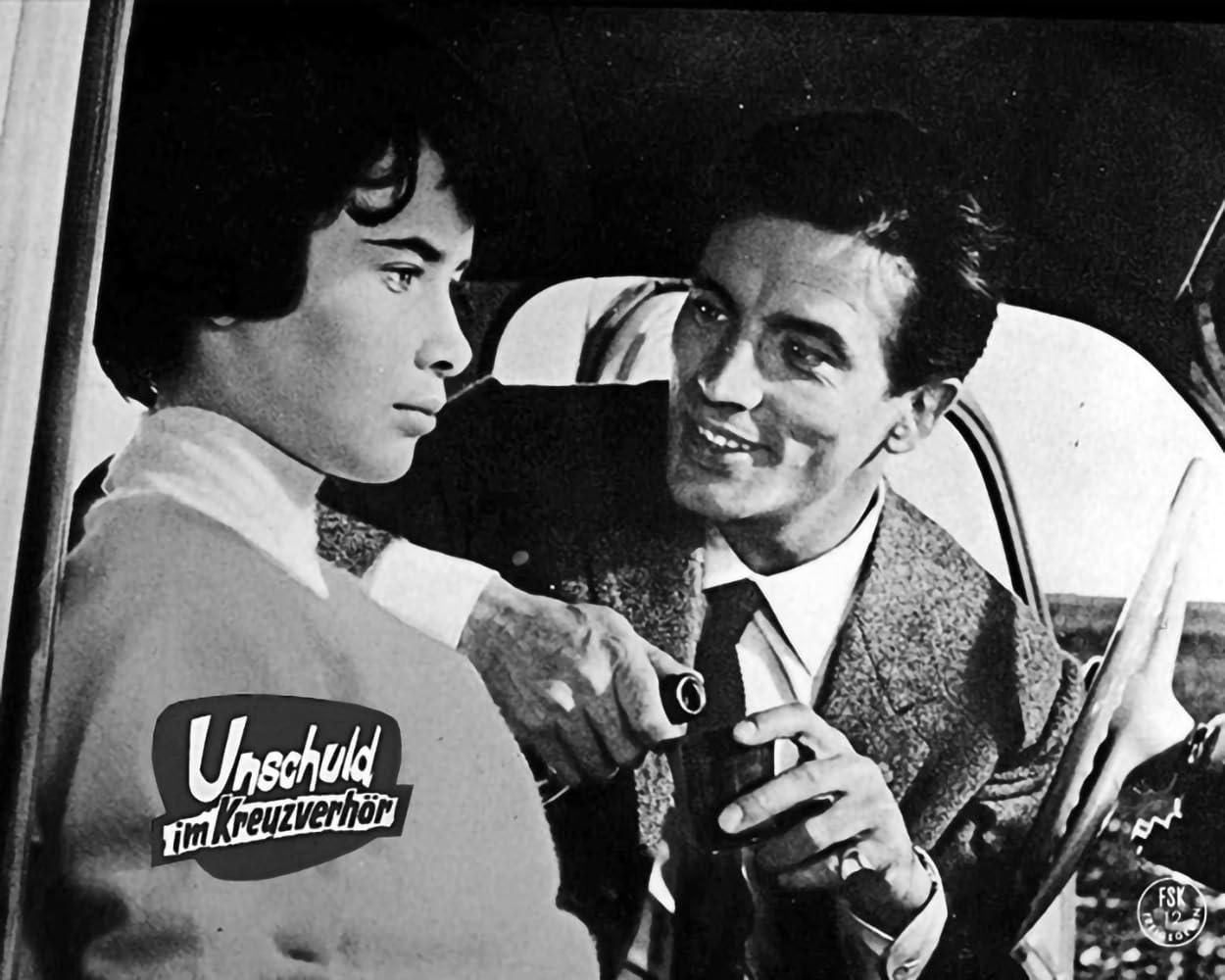 Ein Mann und eine Frau sitzen im Auto. Der Mann lacht und hält eine Flasche.