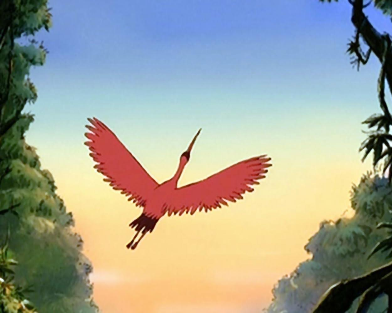 Ein roter Vogel fliegt vor einem sonnigen Himmel über Bäume.