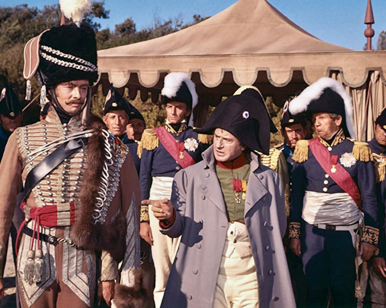 Männer in historischen Uniformen stehen vor einem Zelt. Napoleon ist im Vordergrund.
