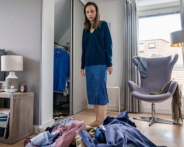 Eine Frau steht in einem Raum mit Kleidung auf dem Boden.
