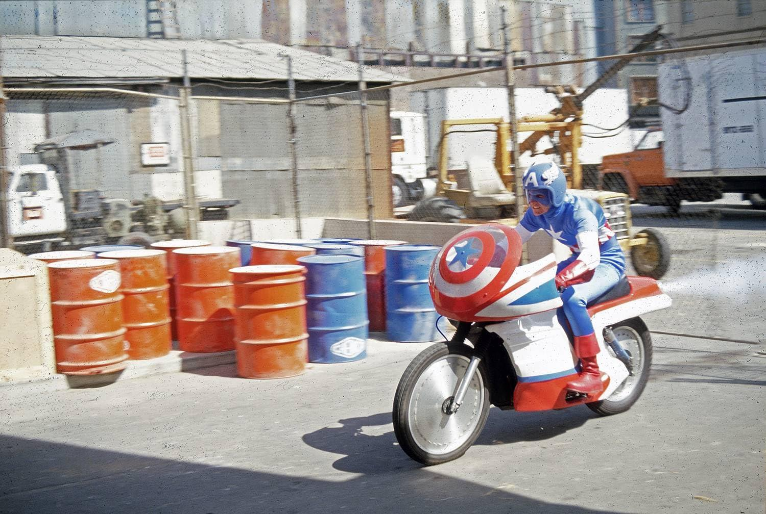 Mann in Captain America-Kostüm fährt Motorrad. "A" auf Helm.