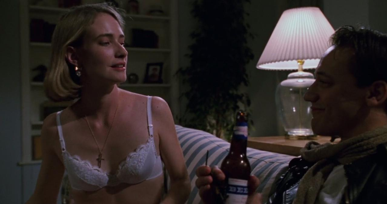 Eine Frau in einem weißen BH und ein Mann mit Bierflasche auf einem Sofa.