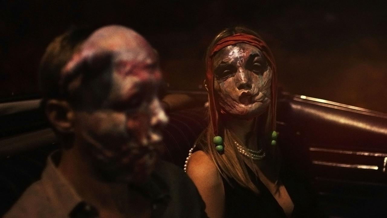Zwei Personen mit gruseligem Make-up sitzen im Dunkeln im Auto.