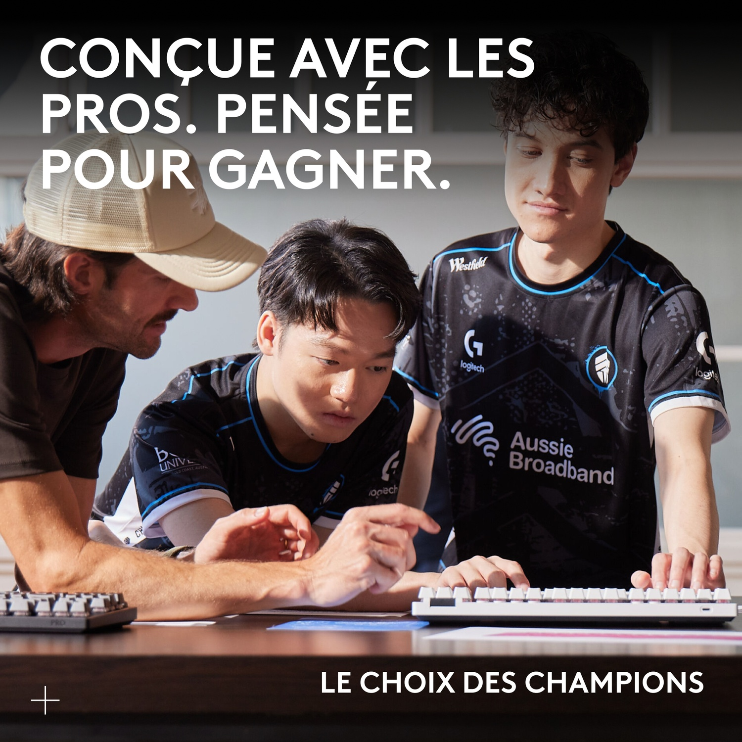 Trois joueurs e-sport regardent un clavier. L'un d'eux pointe.