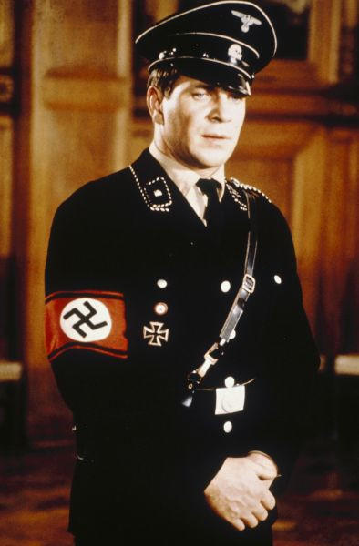 Ein Mann in SS-Uniform mit Hakenkreuzband am Arm und Totenkopf auf der Mütze.