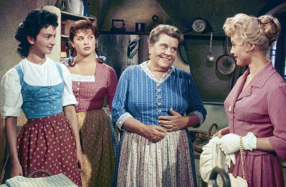 Vier Frauen in traditioneller Kleidung stehen in einem Raum.