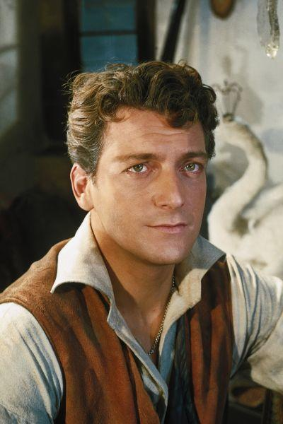 Ein Mann mit braunem Haar und grünen Augen trägt eine Weste über einem Hemd.
