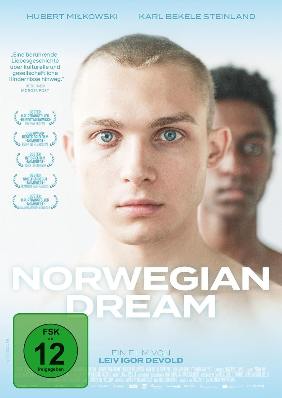 Zwei Männer im Porträt, einer im Fokus mit blauen Augen, der andere verschwommen im Hintergrund.