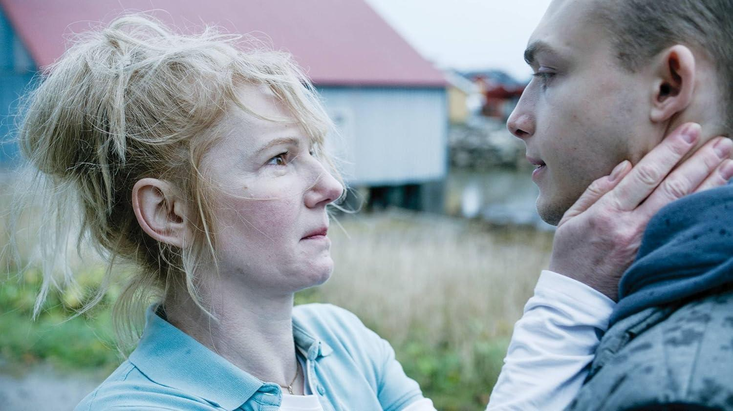 Frau mit blondem Haar und Mann, der ihre Hand am Hals hält, draußen.