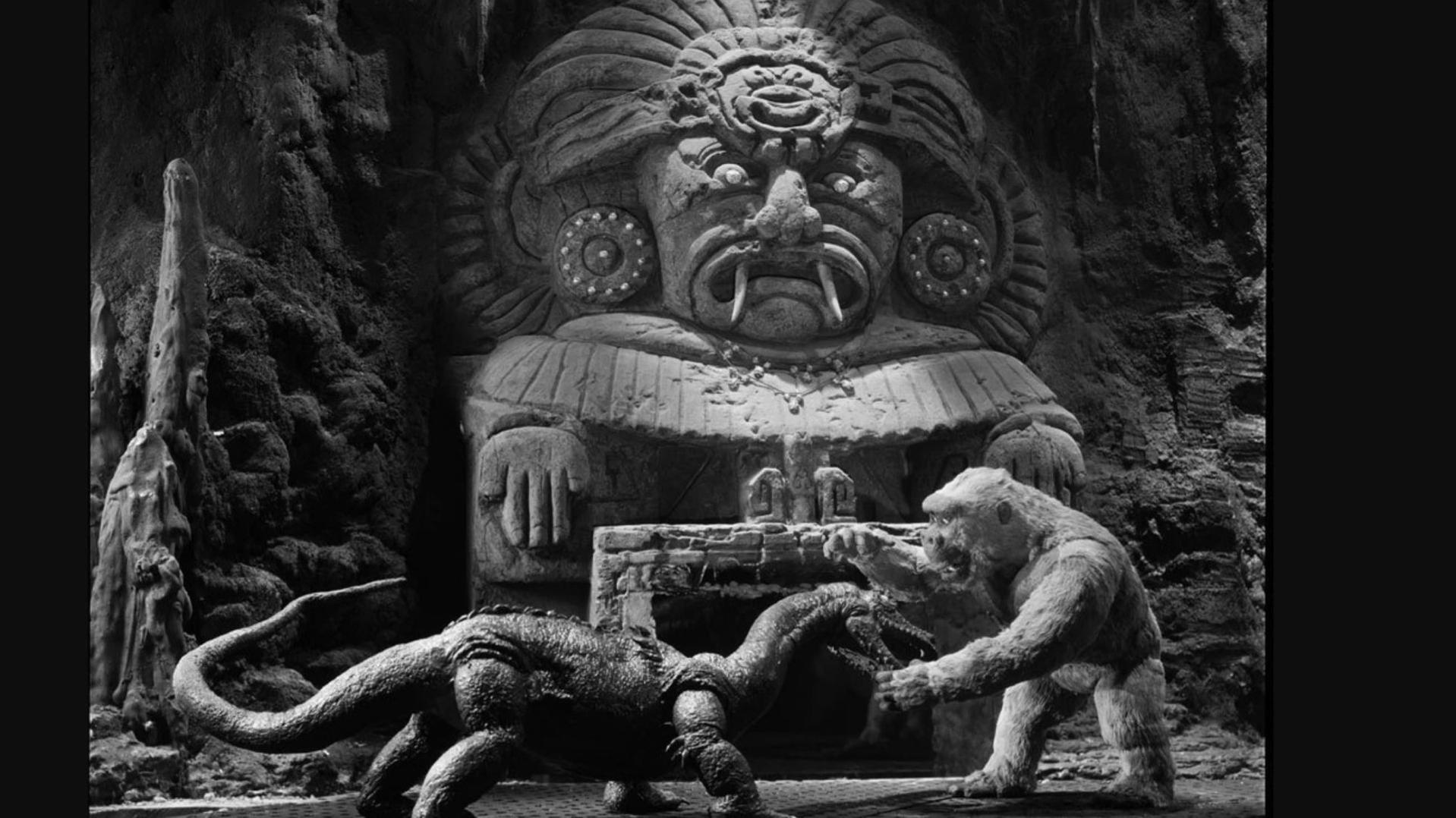 Ein Gorilla kämpft gegen einen Dinosaurier vor einer riesigen Steinstatue.