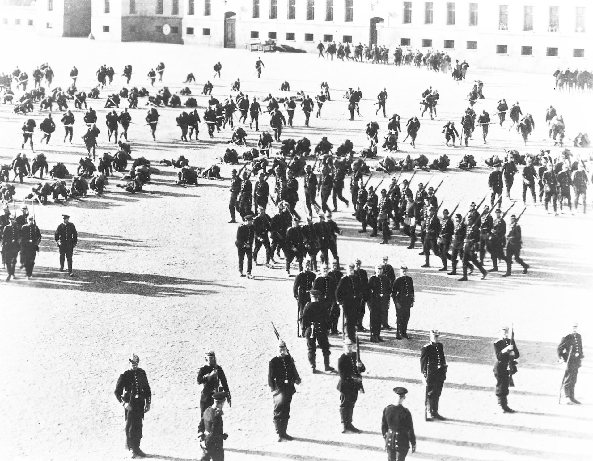Militärparade auf einem Platz vor Gebäuden mit vielen Soldaten in Uniform.