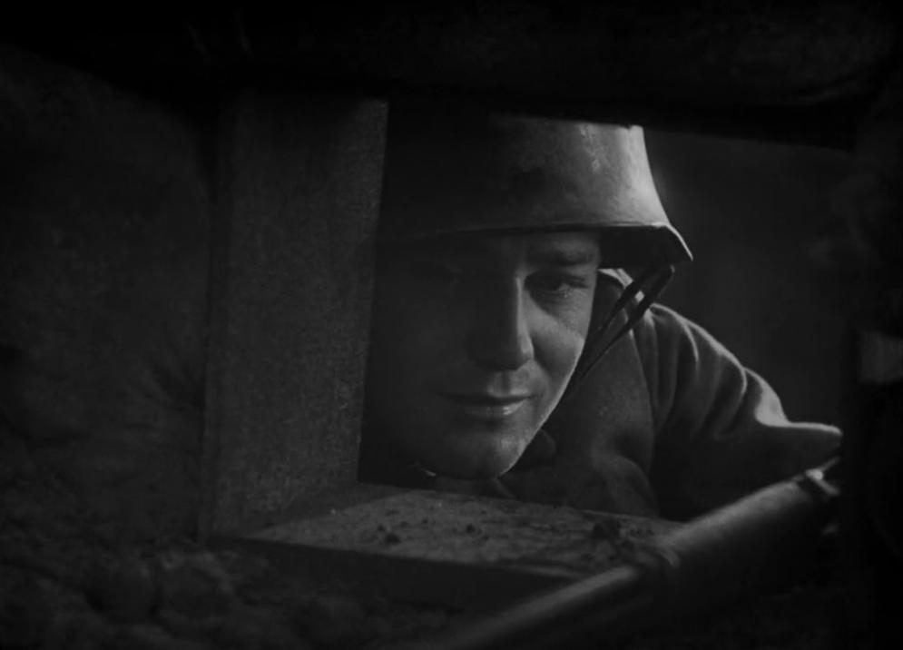 Ein Soldat mit Helm späht aus einem Schützengraben.