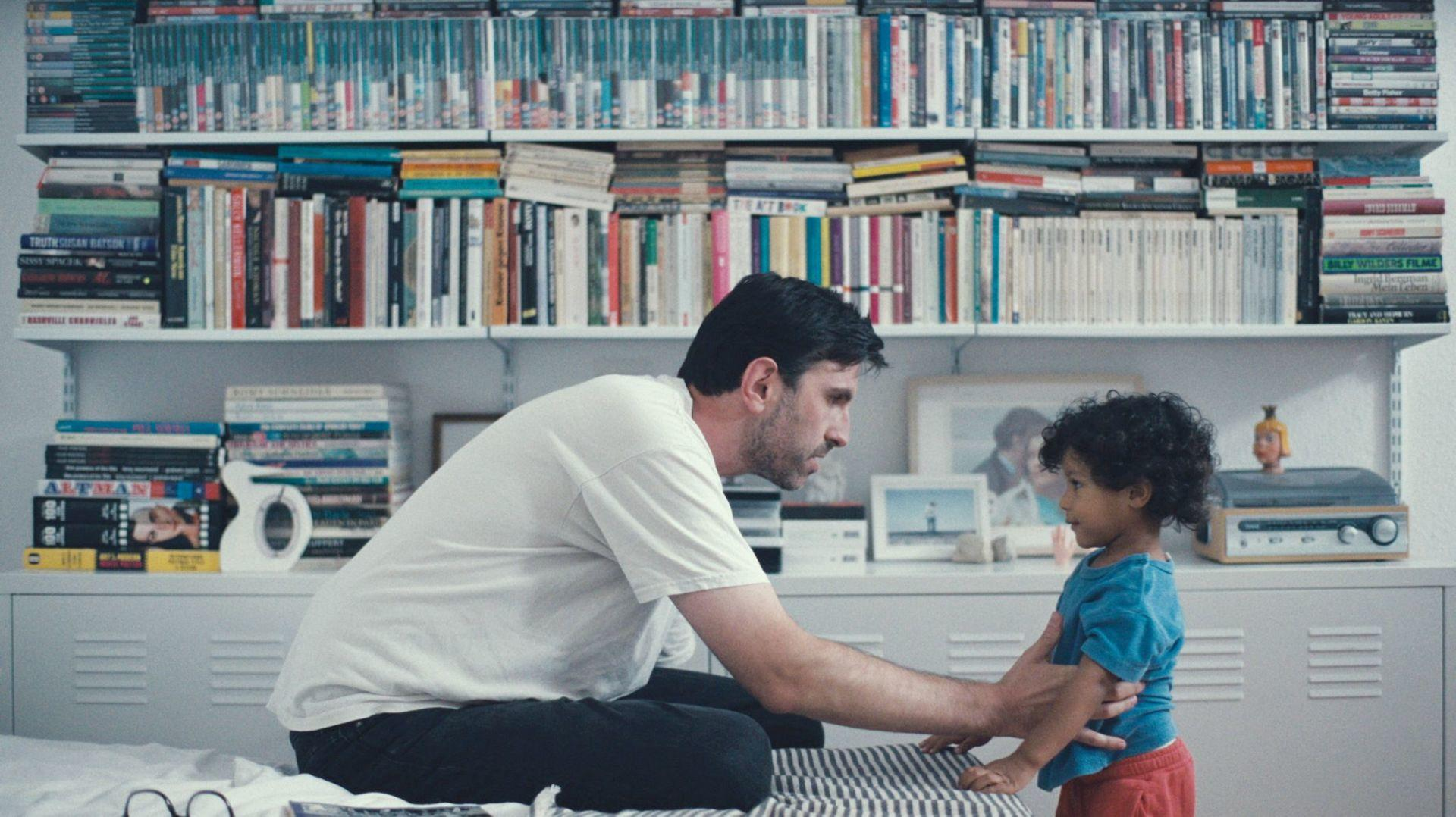 Ein Mann und ein Kind stehen vor einem Bücherregal voller Bücher.