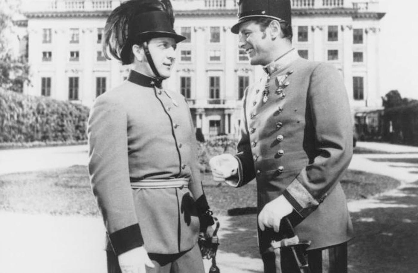 Zwei Männer in Uniformen sprechen vor einem Gebäude.