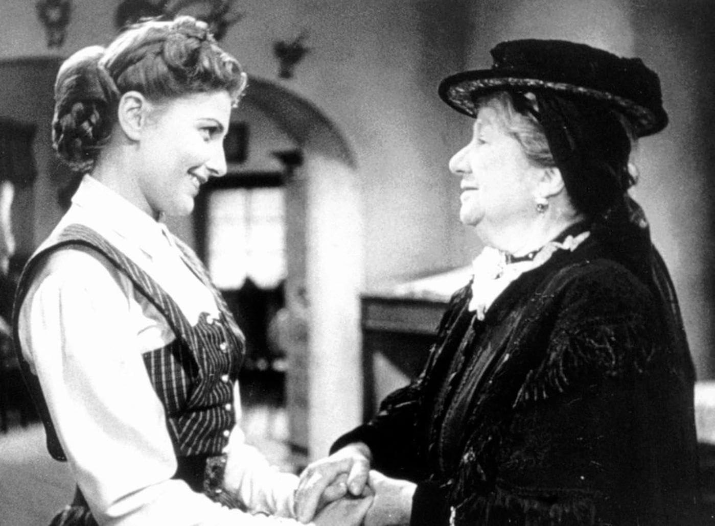 Zwei Frauen halten Händchen, eine trägt eine Tracht, die andere einen Hut.