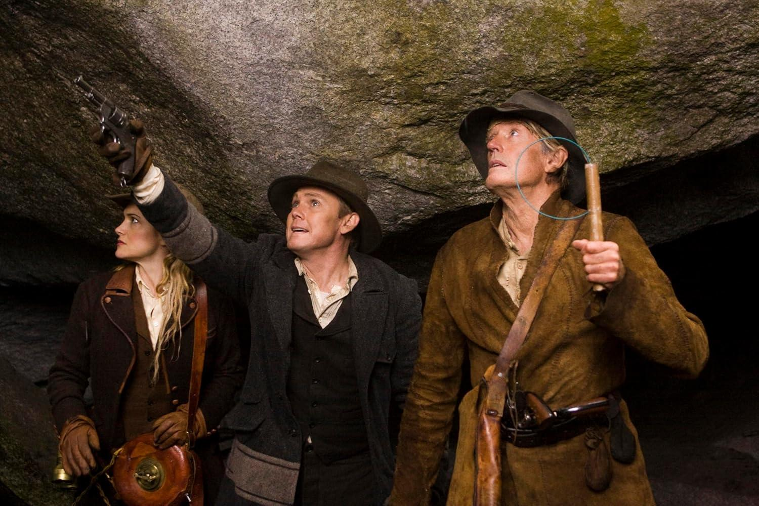 Drei Abenteurer in Höhle, einer hebt eine Pistole, Blicke nach oben.
