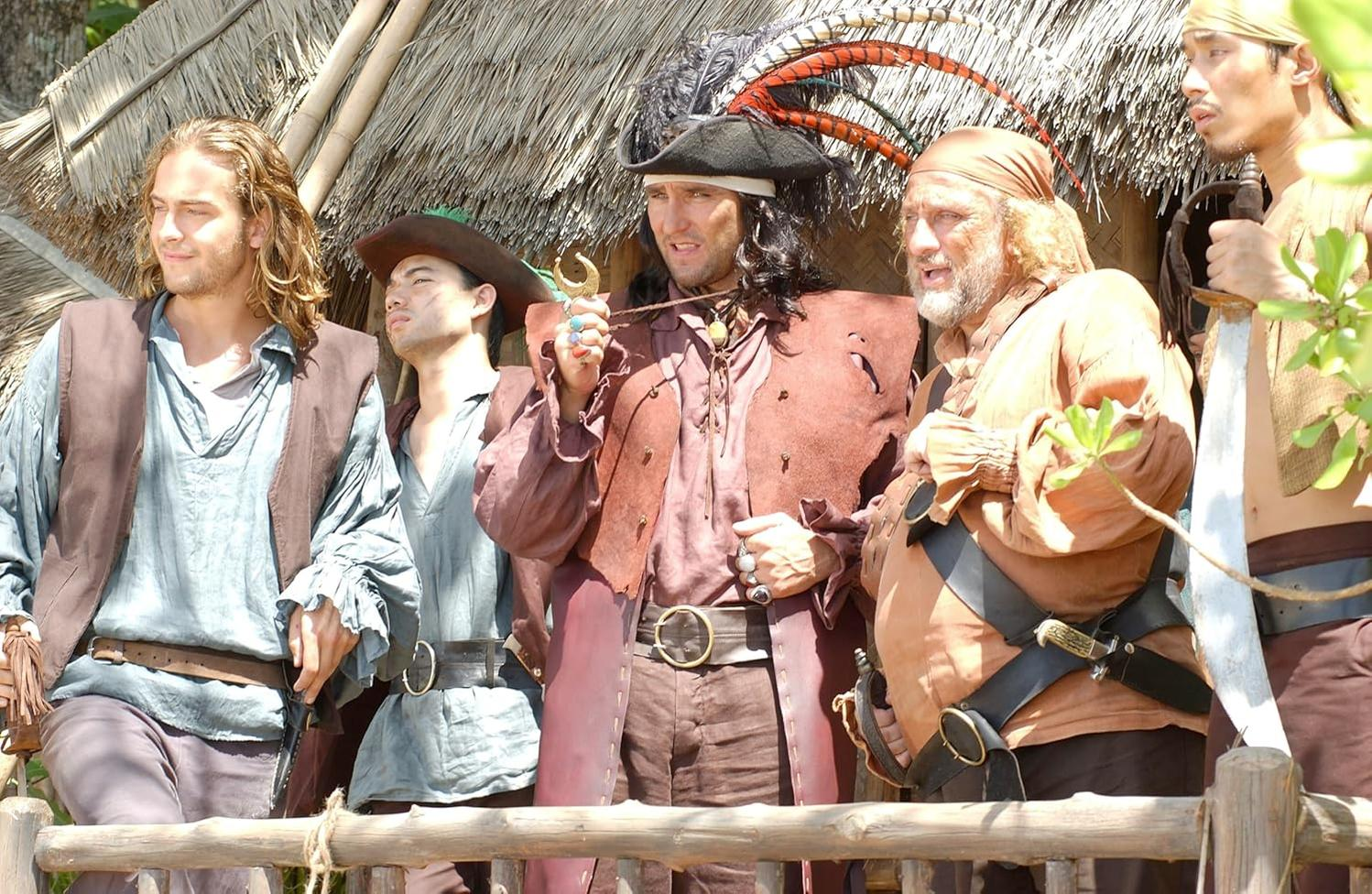 Fünf Männer in Piratenkleidung stehen vor einem Strohdachhaus.