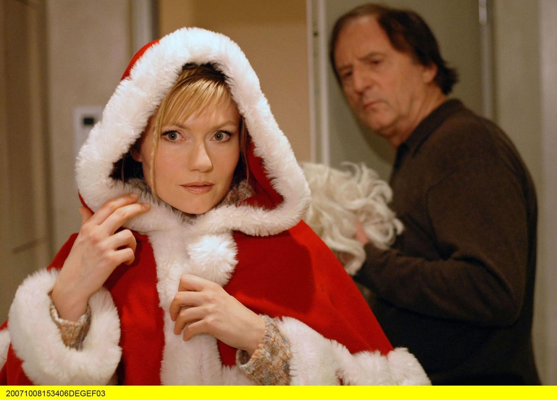 Eine Frau im Weihnachtsmannkostüm blickt nach vorne, ein Mann im Hintergrund.