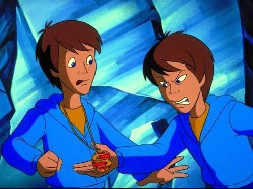 Zwei Jungen in blauen Kapuzenpullovern, einer hält ein rotes Amulett.
