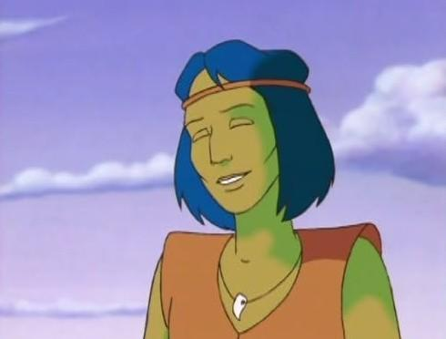 Eine grüne Figur mit blauen Haaren trägt ein orangefarbenes Oberteil.