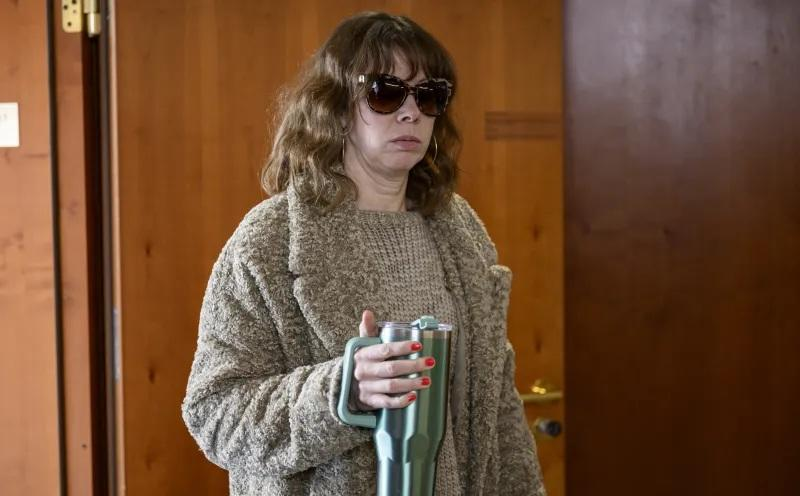 Frau mit Sonnenbrille und braunem Teddyfellmantel hält eine grüne Tasse.