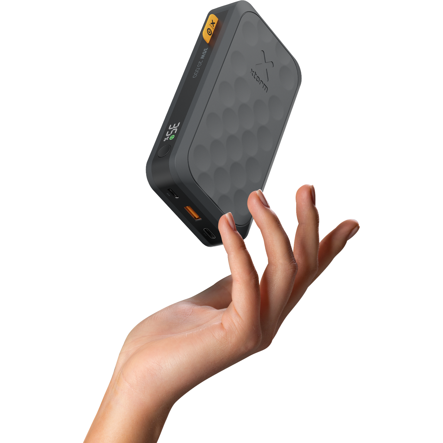A hand holds a gray power bank with a honeycomb pattern and a display.
