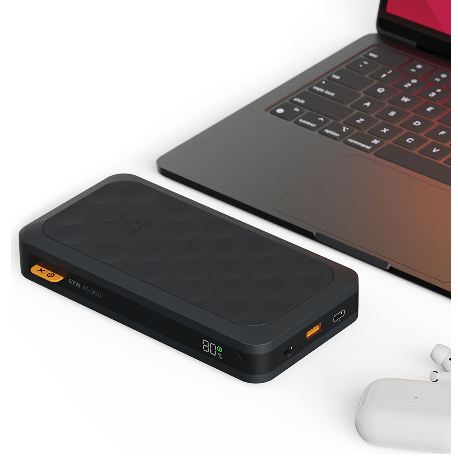 Black power bank next to a laptop and white earbuds.