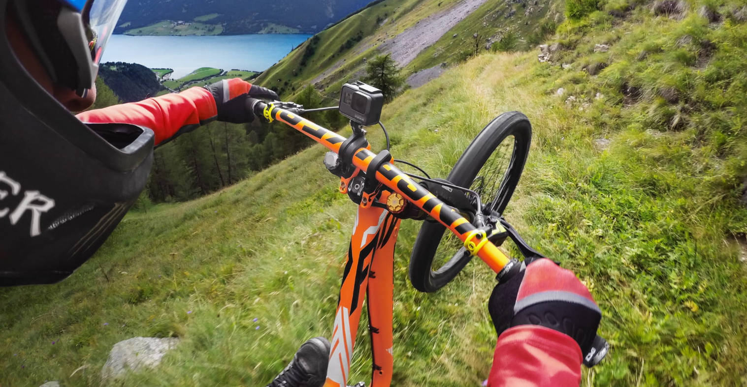 Kolarz górski zjeżdża w dół, widok na jezioro i góry.