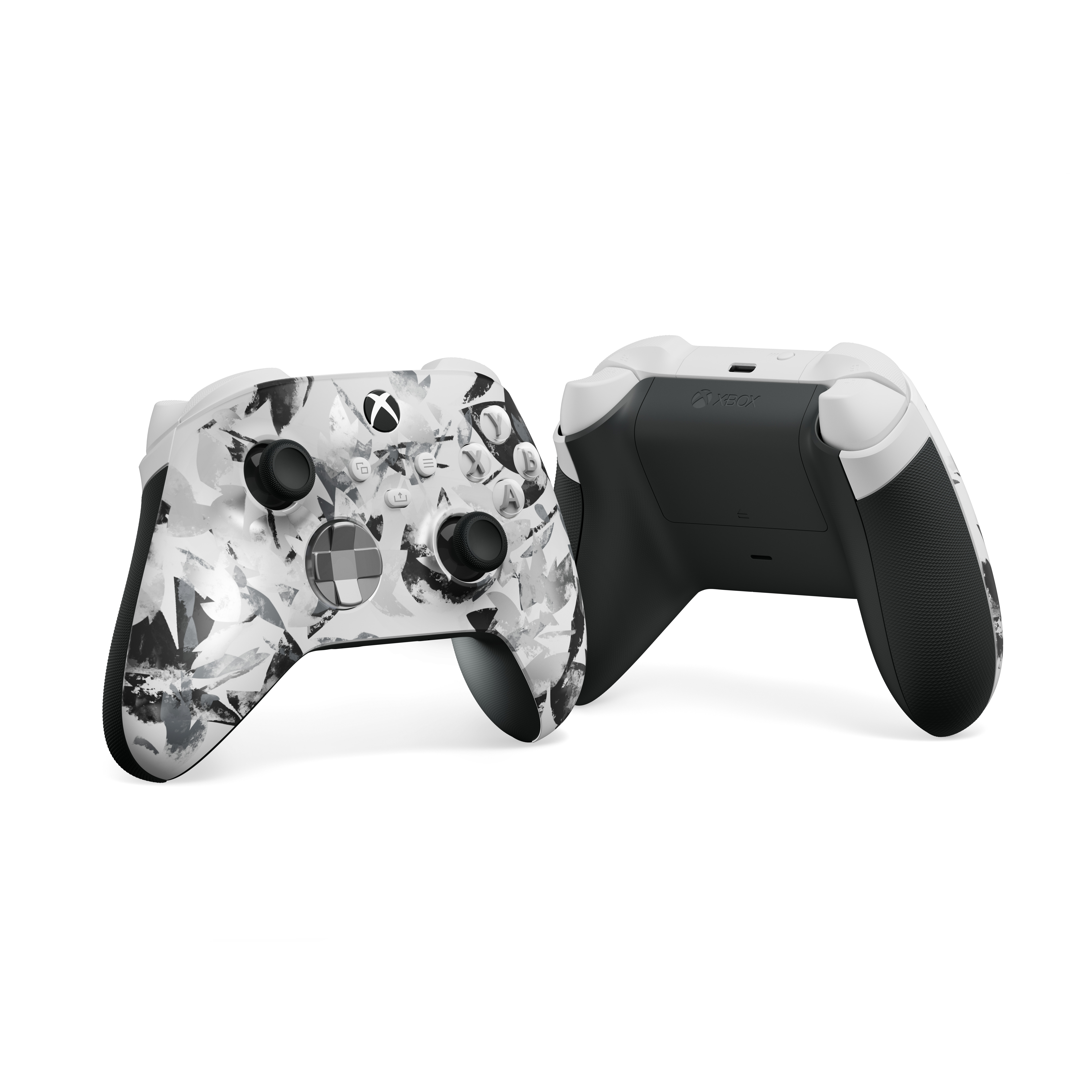 Soyut siyah desenli iki beyaz Xbox kontrolcüsü, biri önde, biri arkada.