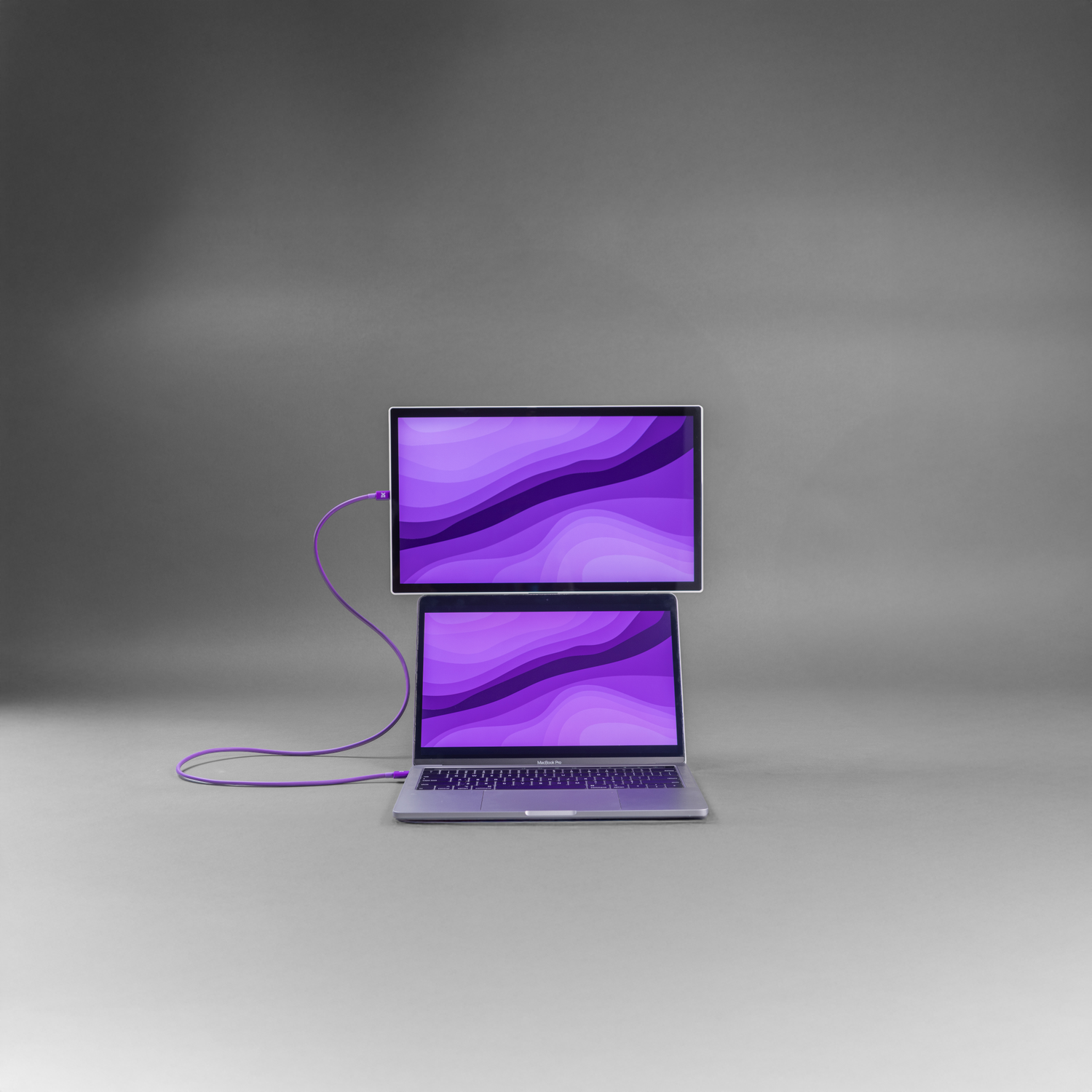 A laptop with an external monitor, connected by a purple cable.
