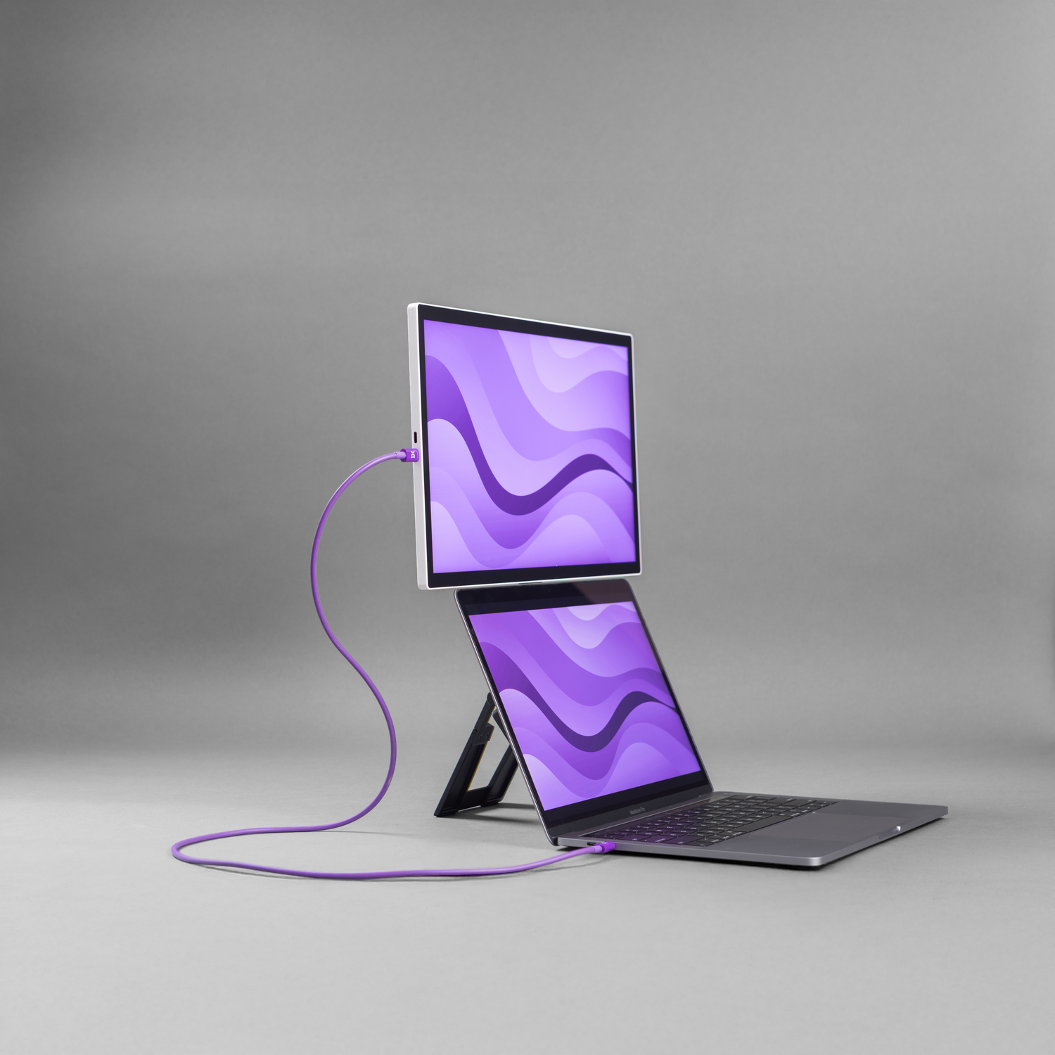 A laptop and an external monitor with purple wave screens on a gray background.
