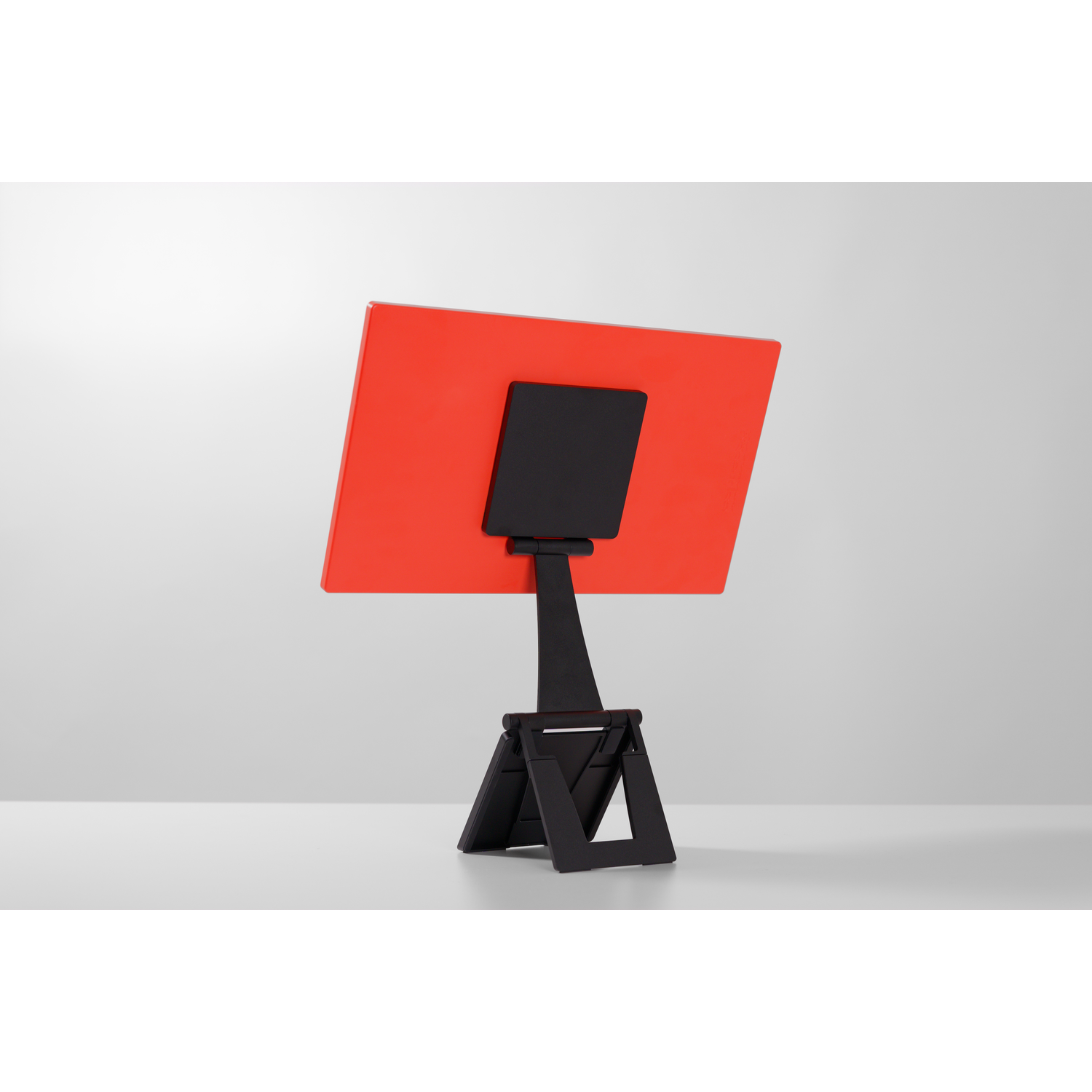 A red rectangle on a black stand, placed on a white table.