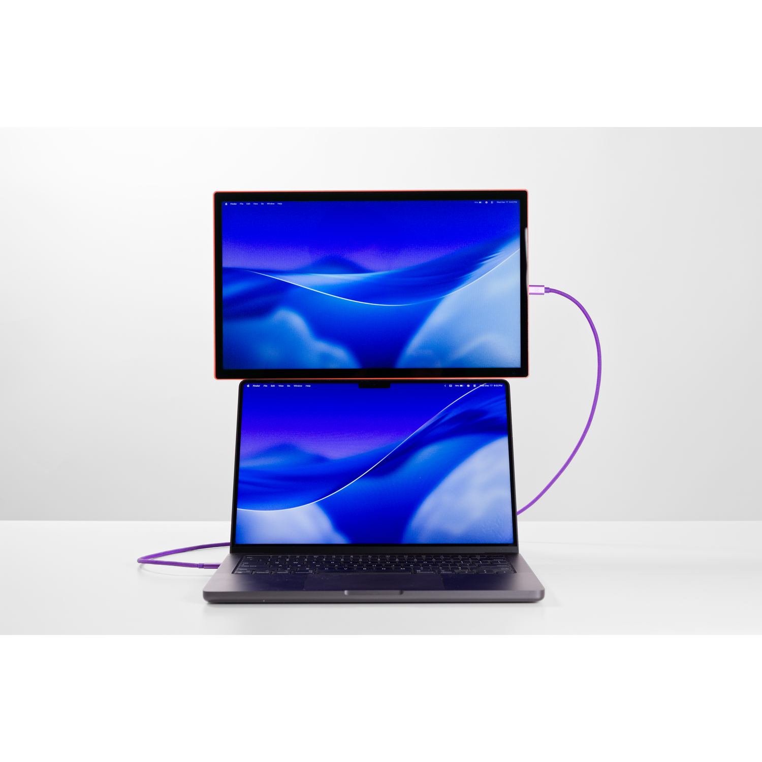 A laptop with an external monitor, connected by a purple cable.
