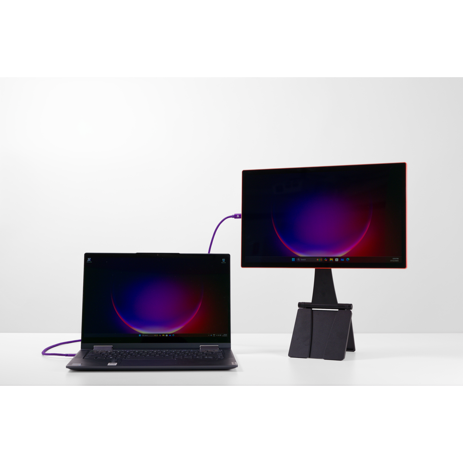 A laptop and an external monitor are connected on a white table.