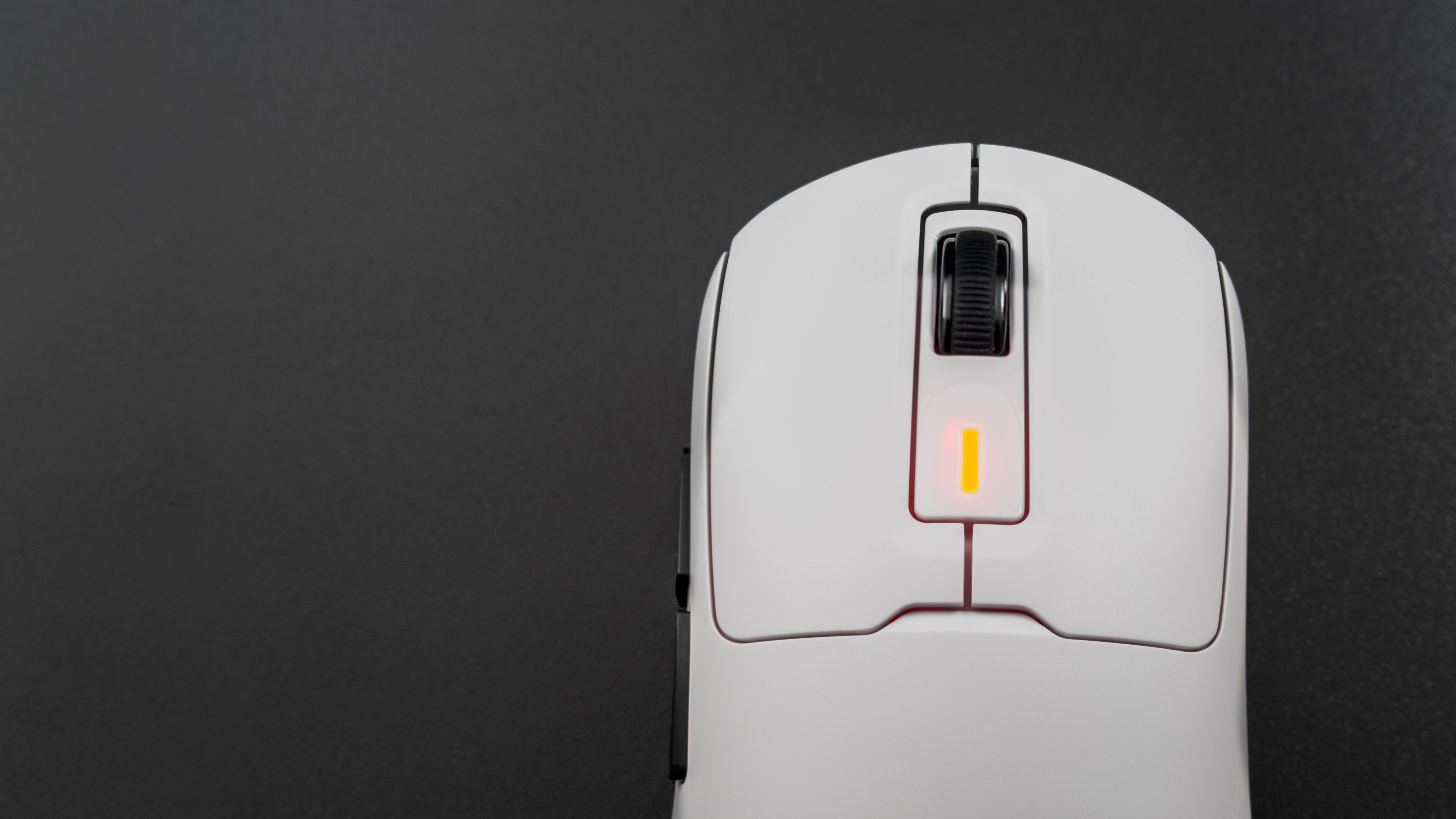 Biała mysz komputerowa z kółkiem przewijania i podświetlanym elementem na ciemnym tle.