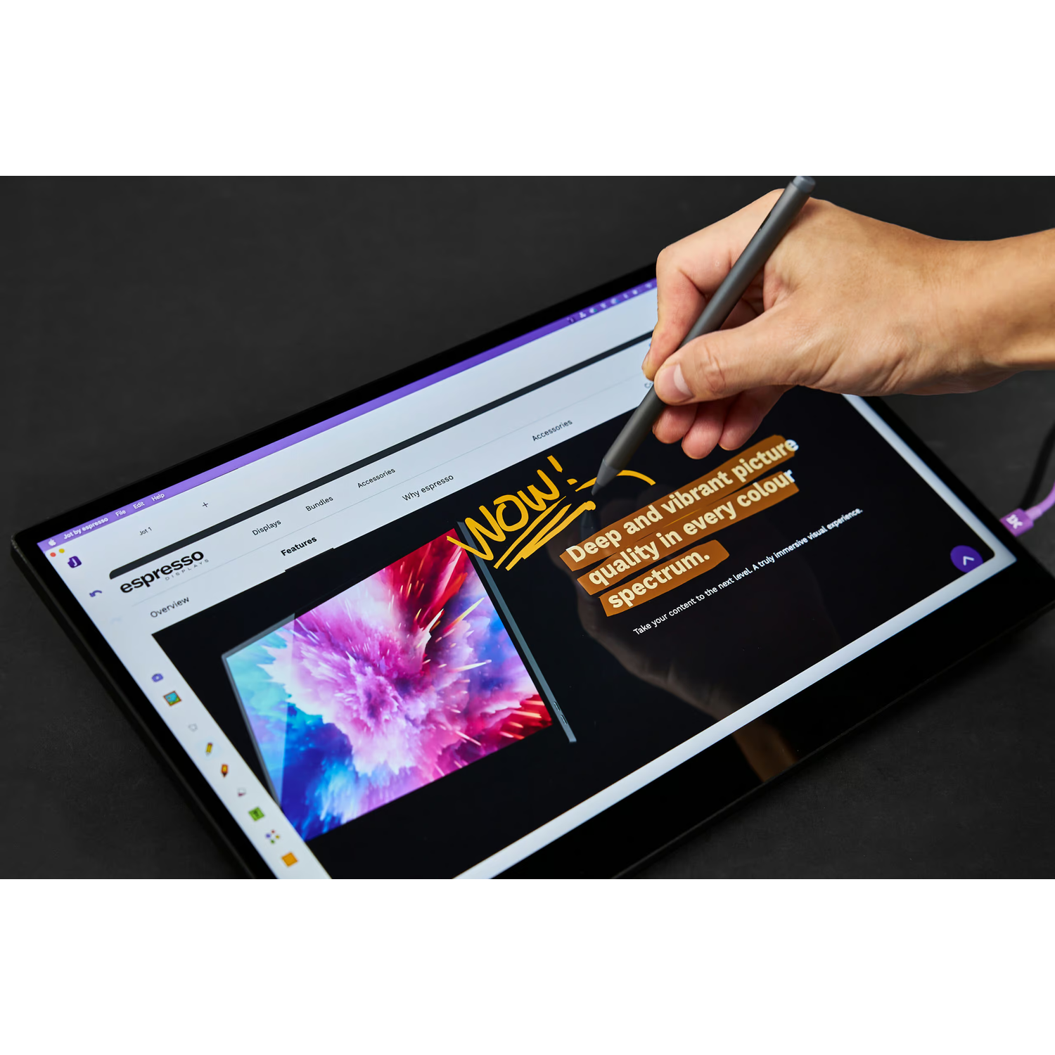 Hand with stylus on a tablet showing a vibrant, colorful image.