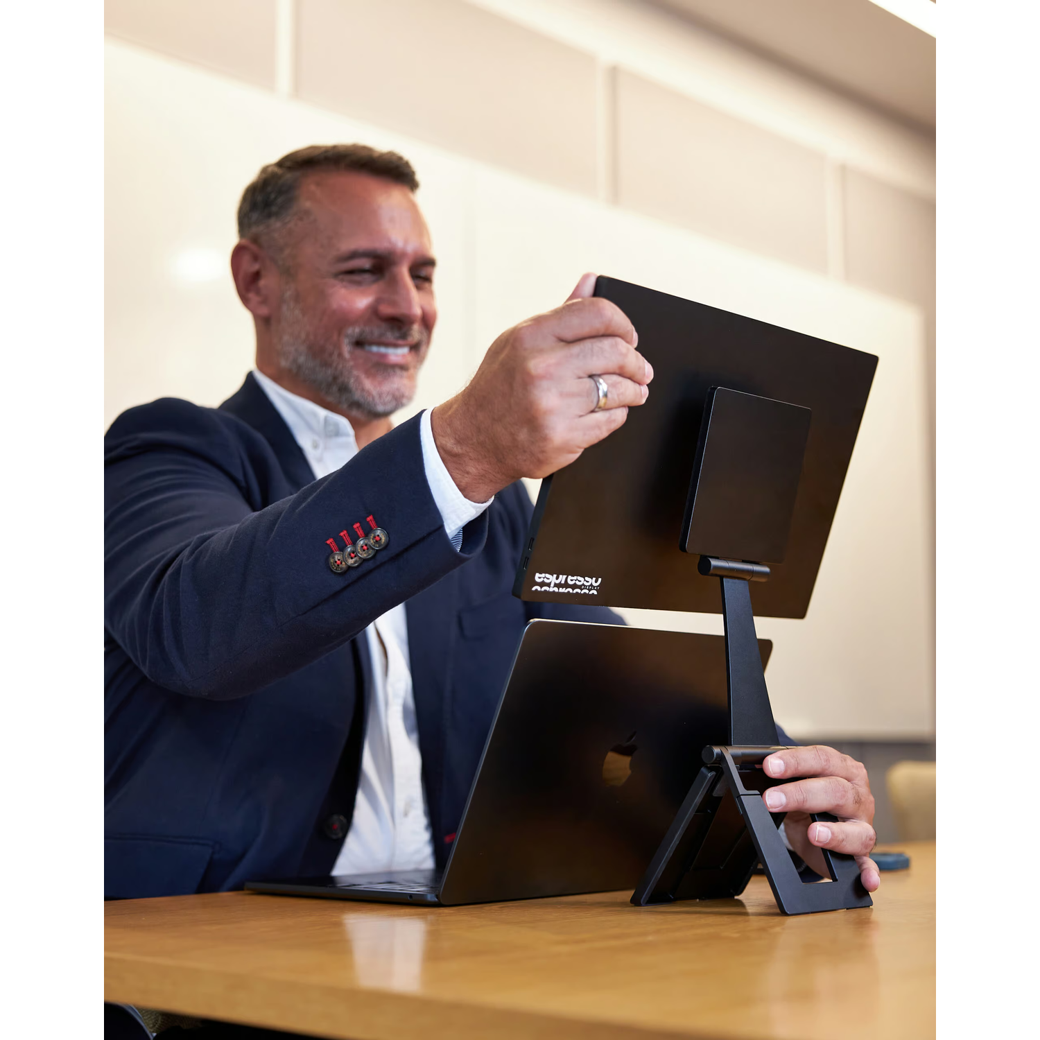 A man in a suit sets up a second monitor on his laptop.